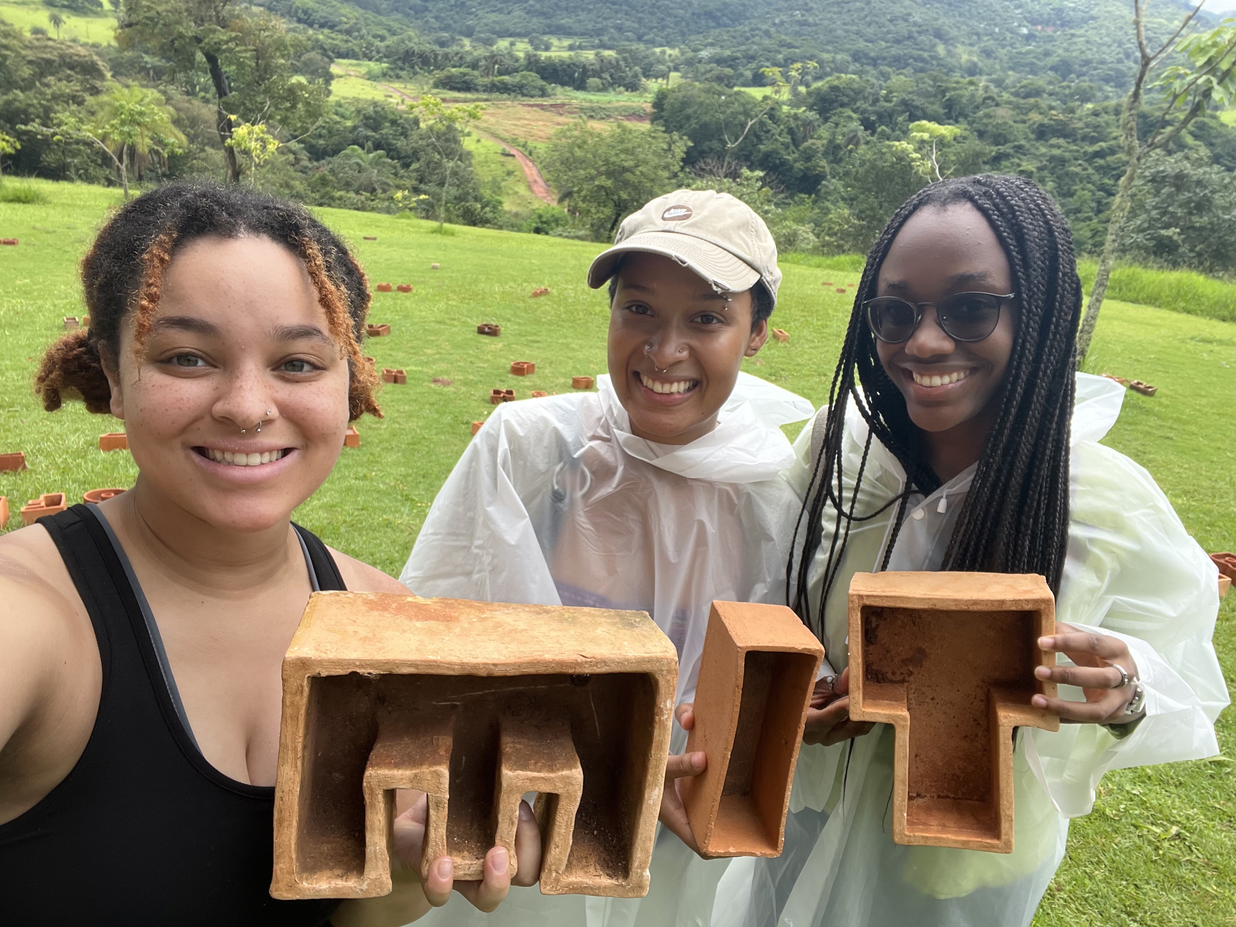 Students crafted terra cotta "MIT" letters and display them in a grassy forested area in Brazil
