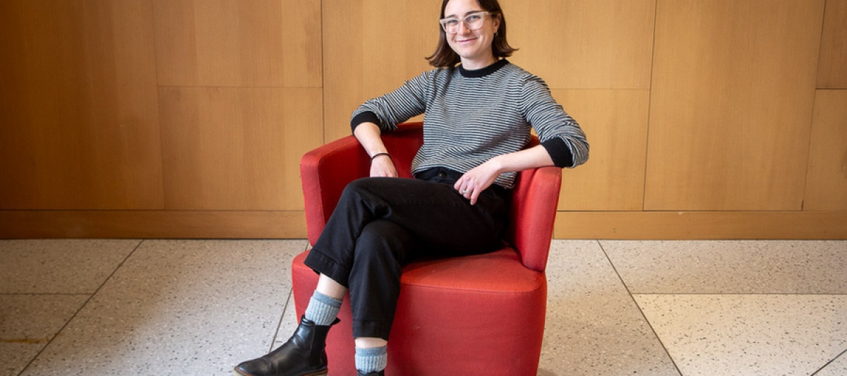MIT economics doctoral student Anna Russo sits in a red chair against a wood-paneled wall.