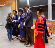 An MIT student, flanked by Phi Beta Kappa officers, receives their notice of induction into the Phi Beta Kappa society.