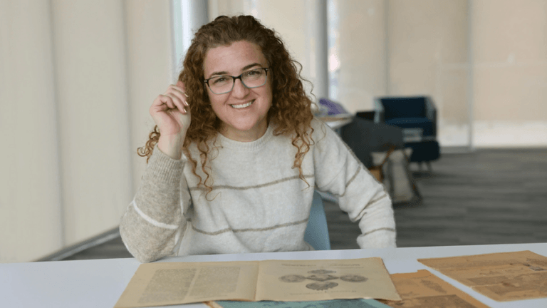 MIT historian Lerna Ekmecioglu seated at a table covered with documents